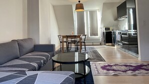 Un salon moderne avec un canapé, une table basse en verre et un coin repas avec des chaises.