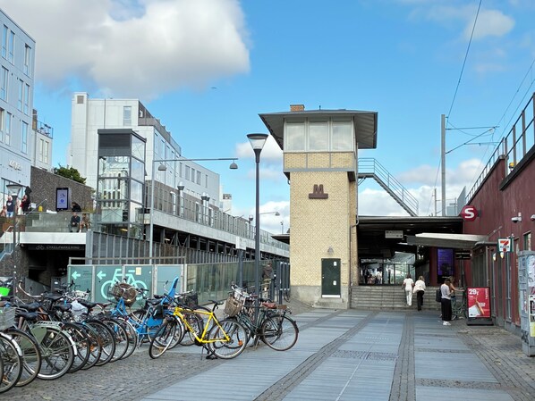 En gångbana för fotgängare med cyklar parkerade längs sidan, en modern byggnad med en glasfasad och en klar himmel.