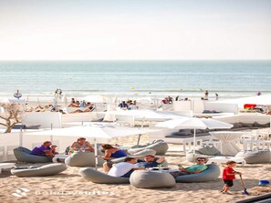 A beachside resort with outdoor seating areas, including bean bags and lounge chairs, and a view of the ocean. - Comfortable Studio With a View Over the City (Blankenberge)