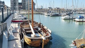 A marina with various boats docked, a wooden boat named 'Blankenberge' prominently in the foreground, and a cityscape in the background. - Comfortable Studio With a View Over the City (Blankenberge)