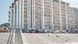 A multi-story hotel with balconies, a parking area, and a staircase leading to the entrance. - Comfortable Studio With a View Over the City (Blankenberge)