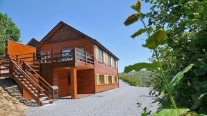 Una baita di legno con un balcone, una scala e un vialetto sterrato.