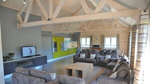 Un'ampia zona giorno con una cucina moderna sullo sfondo, un grande divano e un tavolino da caffè in legno.
