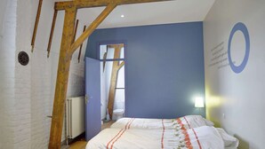 Un dormitorio con techo de madera, pared de ladrillo blanco y una pared azul de acento.