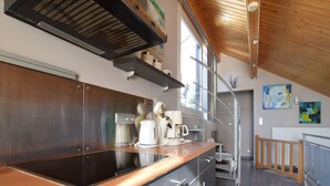Eine moderne Küche mit Edelstahlgeräten, einer Holzausziehtafel und Blick zum Obergeschoss.