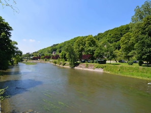 Ein Fluss mit einer Brücke, umgeben von üppigem Grün und Bäumen.