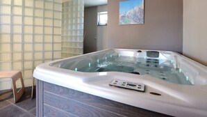 Ein modernes Badezimmer mit einer gläsernen Duschkabine, einem Holzbadezimmer-Möbel und einer digitalen Bedienkonsole für die Badewanne.