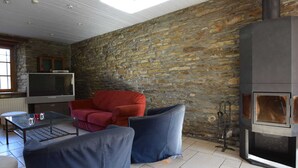 Um quarto aconchegante com parede de pedra, televisão, lareira e assentos confortáveis.