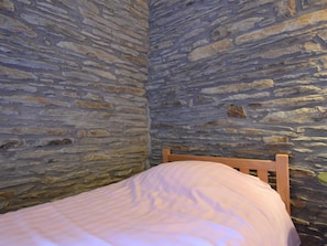 A room with stone walls and a wooden bed frame. - Holiday Home in Tenneville With Private Sauna (Tenneville)