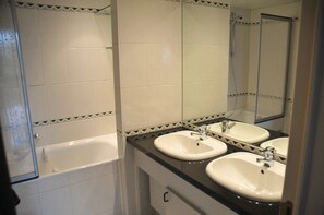 Un bagno con due lavandini, una vasca e uno specchio.