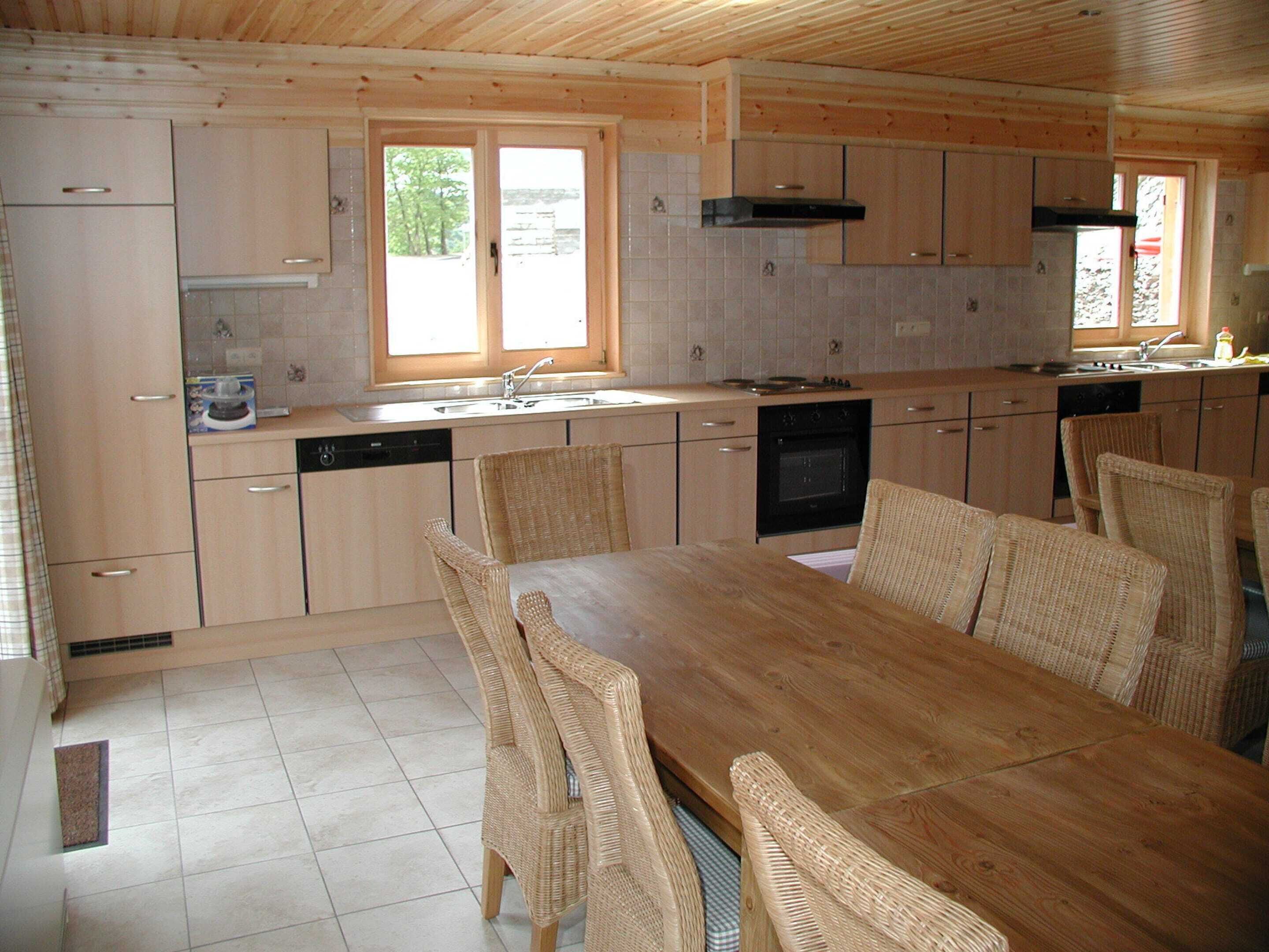 Eine Küche mit Holzausstattung, einem Esstisch mit Korbstühlen und einem Fenster, das für natürliches Licht sorgt.