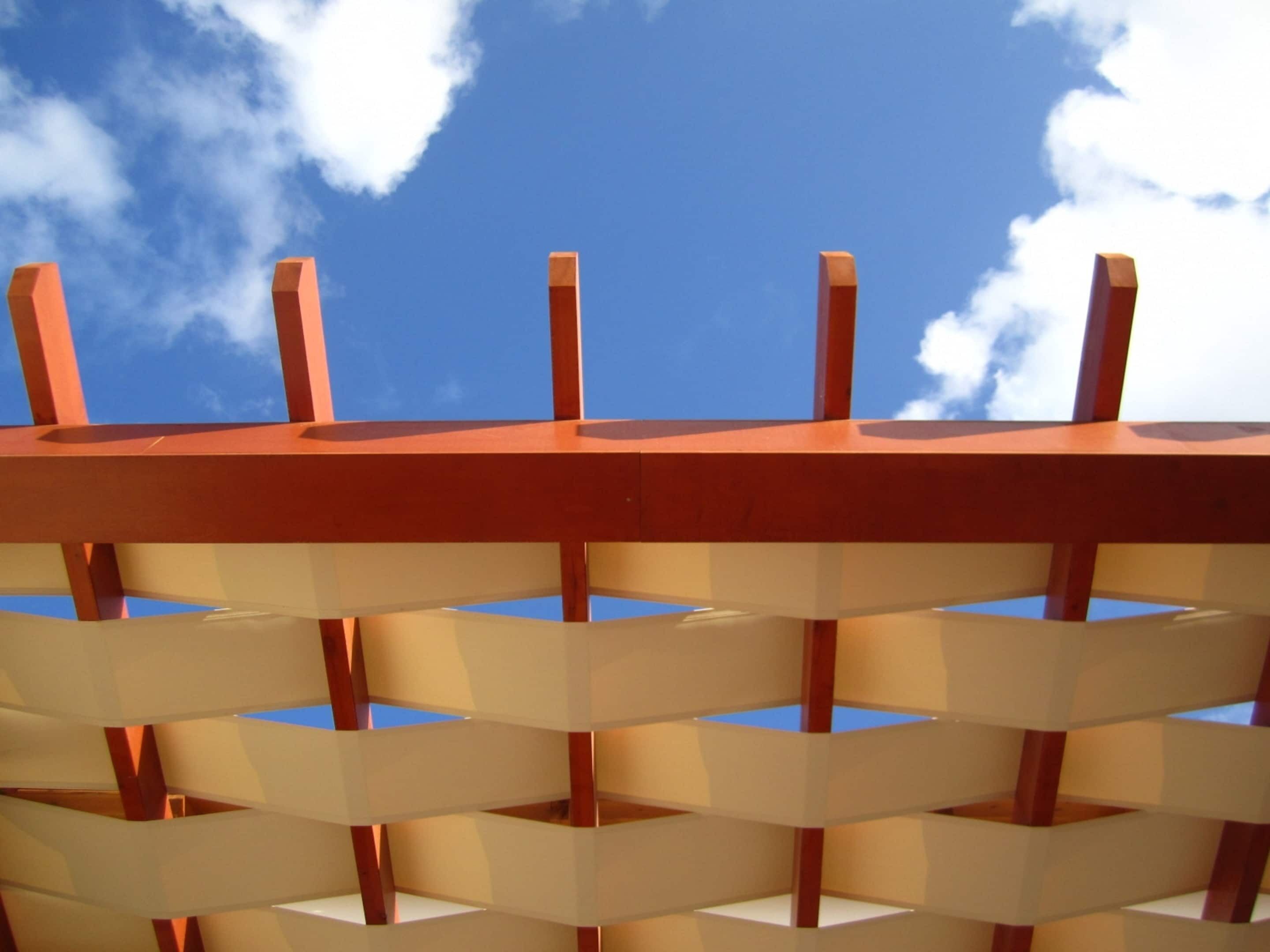 Une structure en treillis de bois, avec un ciel bleu clair en arrière-plan.