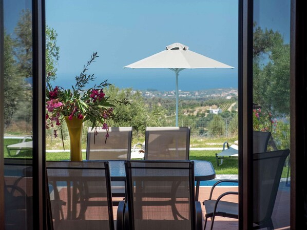 Enjoy a serene ocean view from this outdoor seating area, complete with a table, chairs, and umbrella, adjacent to a pool.