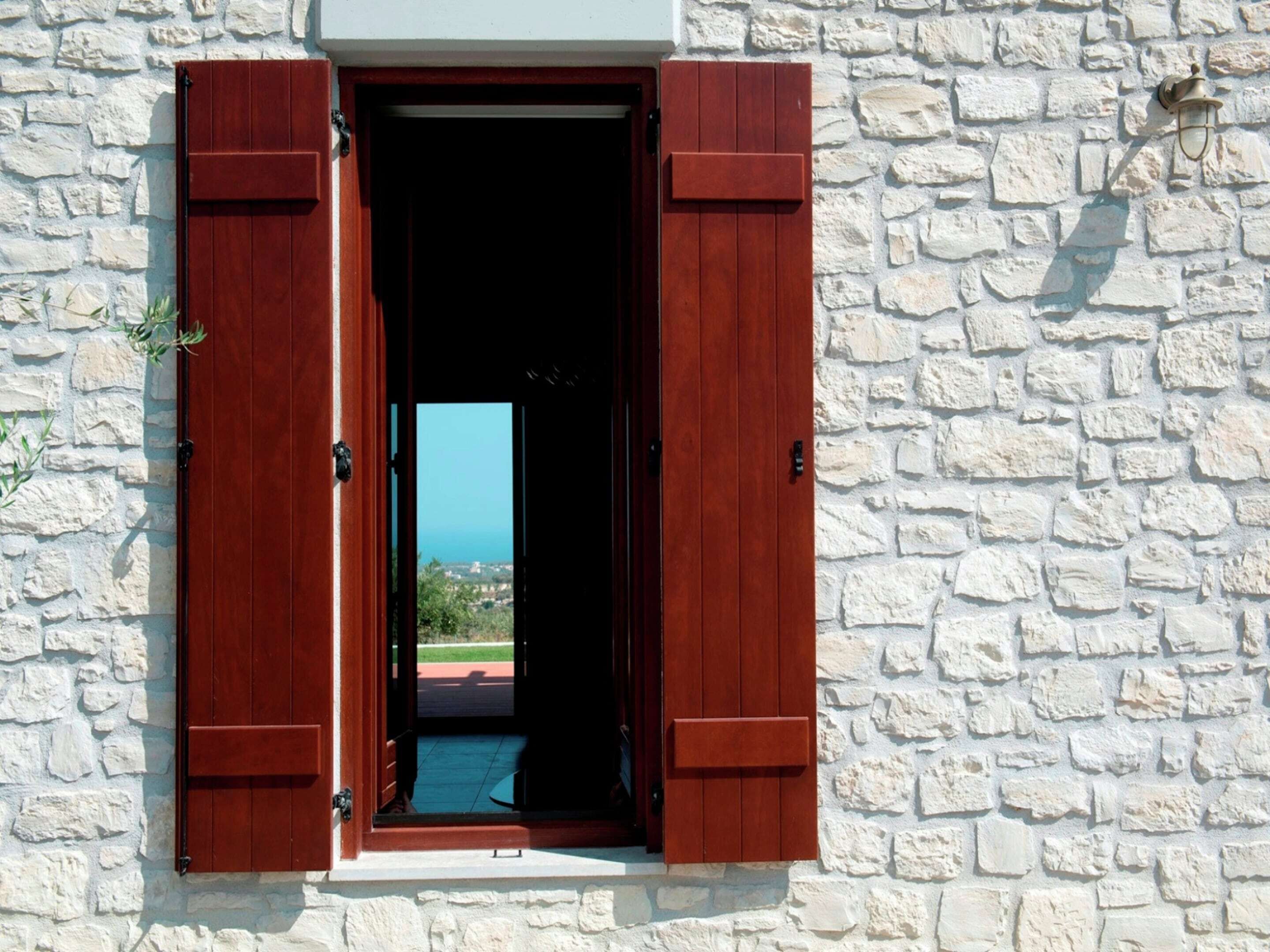 A stone wall with a wooden door and shutters.