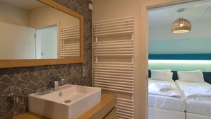 A modern bathroom with a stone backsplash, a white sink, and a large mirror. - Malmedy Hillside Spa Retreat (Malmedy)