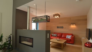 A modern living room with a red sofa, a wooden coffee table, and a fireplace. - Malmedy Hillside Spa Retreat (Malmedy)