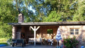 A brick building with a barbecue area, outdoor seating, and a swimming pool.