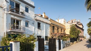 Una hilera de edificios de estilo mediterráneo tradicional con balcones, cielo despejado y una calle estrecha.
