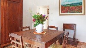 Ein Essbereich mit einem Holztisch, Stühlen, einer weißen Vase mit Blumen, einem Bild an der Wand und einem Holzschrank.