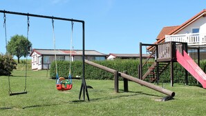 A playground with swings, a slide, and a climbing structure. - Spacious Apartment in Wohlenberg Germany near Beach (Klütz)