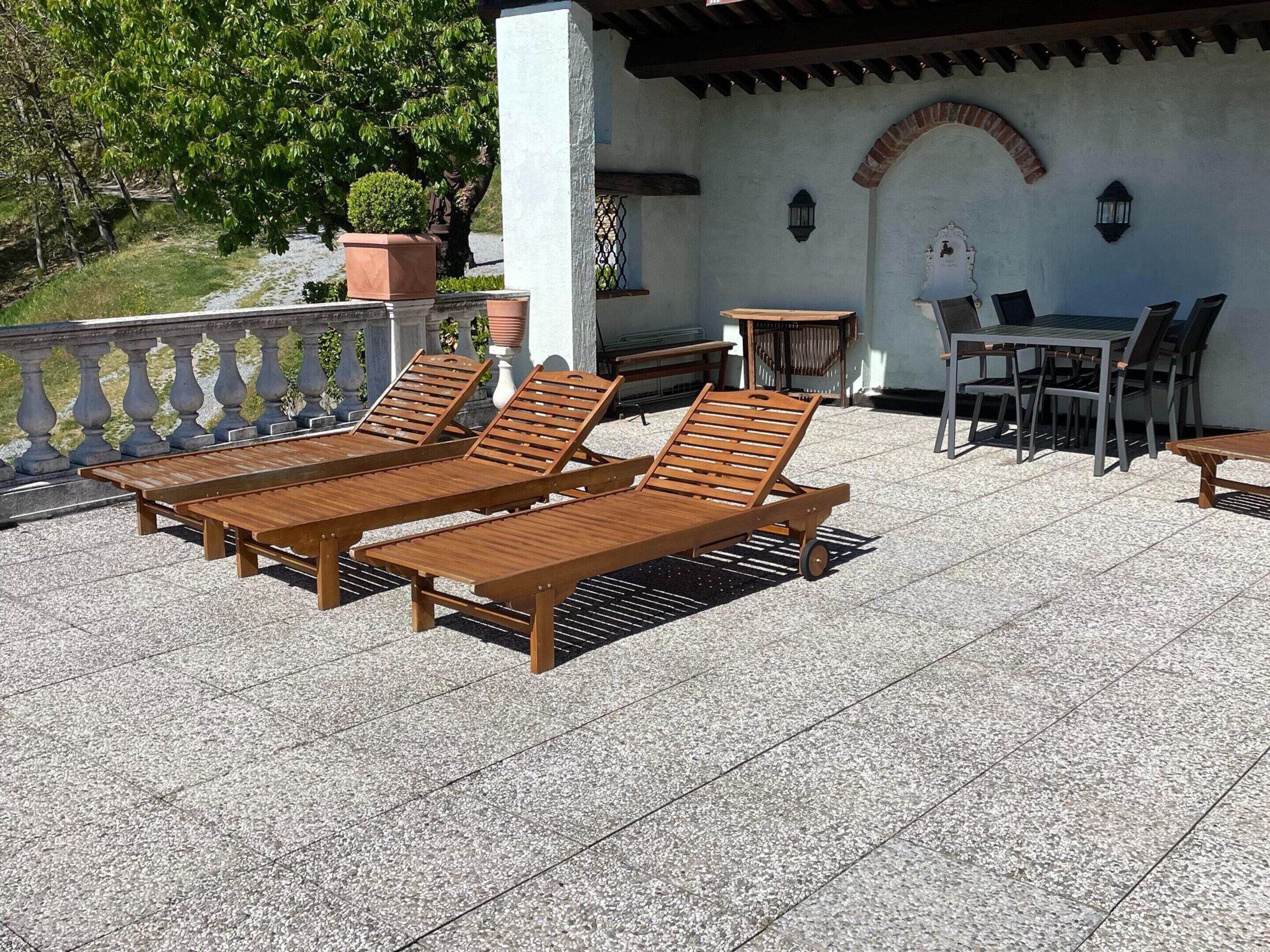 Una terraza con sillones de madera, una mesa y sillas.