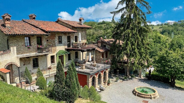 A stone building with multiple balconies and a courtyard with a fountain. - Holiday Home in Langhe With Pool and Terrace (Bastia Mondovì)