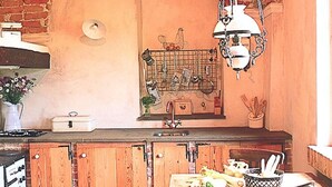 A kitchen with wooden cabinets, a hanging light fixture, and a window with a grid pattern. - Holiday Home in Langhe With Pool and Terrace (Bastia Mondovì)