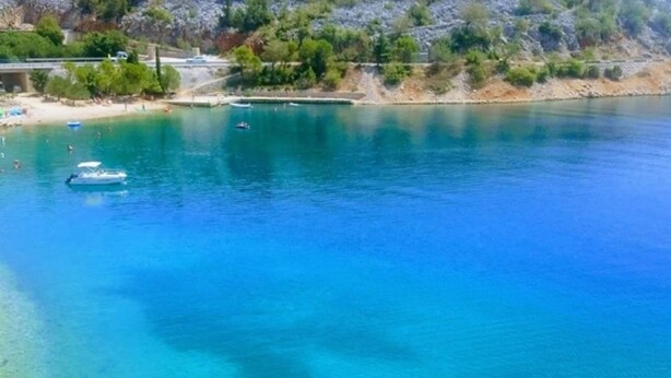 A coastal area with clear blue water, a beach, and a bridge.