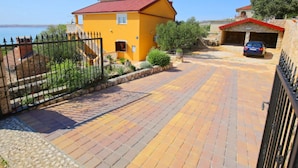 A yellow house with a red roof, a paved driveway, and a car parked in the driveway.