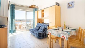 Een gezellige kamer met een bank, een eettafel met stoelen, een televisie en een balkon met uitzicht.