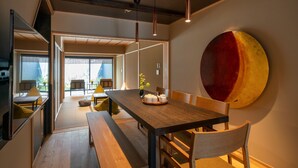 A modern dining area with a wooden table, benches, and pendant lighting.