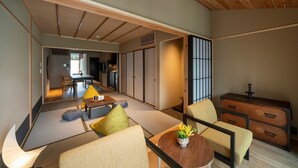 A traditional Japanese-style living room with tatami flooring, low wooden furniture, and sliding doors.