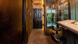 A bar area with a counter and stools, a dark wooden door, and a view of the outdoors. - Boho Bangkok (Bangkok)