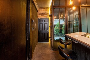 A bar area with a counter and stools, a dark wooden door, and a view of the outdoors. - Boho Bangkok (Bangkok)