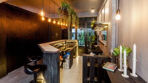 Un área de bar moderna con plantas colgantes, taburetes y una barra.