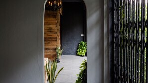 Un pasillo con pared de madera, una puerta negra y una reja de metal.