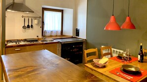 Eine Küche mit Holztisch, Herd und einem Fenster mit Vorhängen.