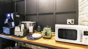 Una cocina equipada con microondas, cafetera y tostadora. Se aprecia una pared de ladrillo al fondo y una encimera de madera.
