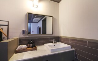 Un baño con un espejo grande, un lavamanos y un perchero para toallas.
