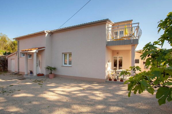 A two-story house with a balcony, a gravel driveway, and potted plants. - Adorable House Apartment With Roof Terrace (Malinska-Dubasnica)