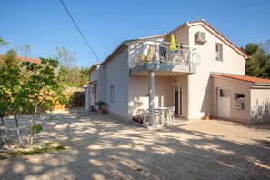A two-story house with a balcony, a gravel driveway, and potted plants. - Adorable House Apartment With Roof Terrace (Malinska-Dubasnica)