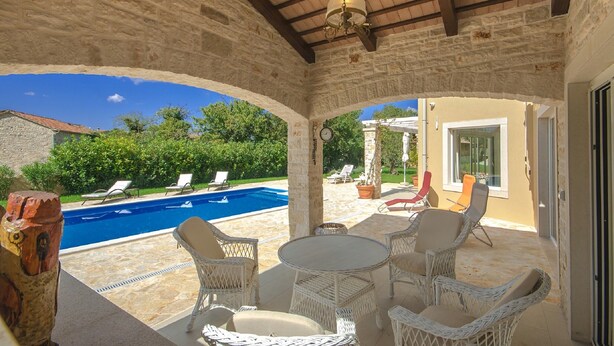 A covered outdoor area with a pool, wicker furniture, and a stone wall. - Peaceful Villa in Sveti Lovrec With Swimming Pool (Sveti Lovrec)