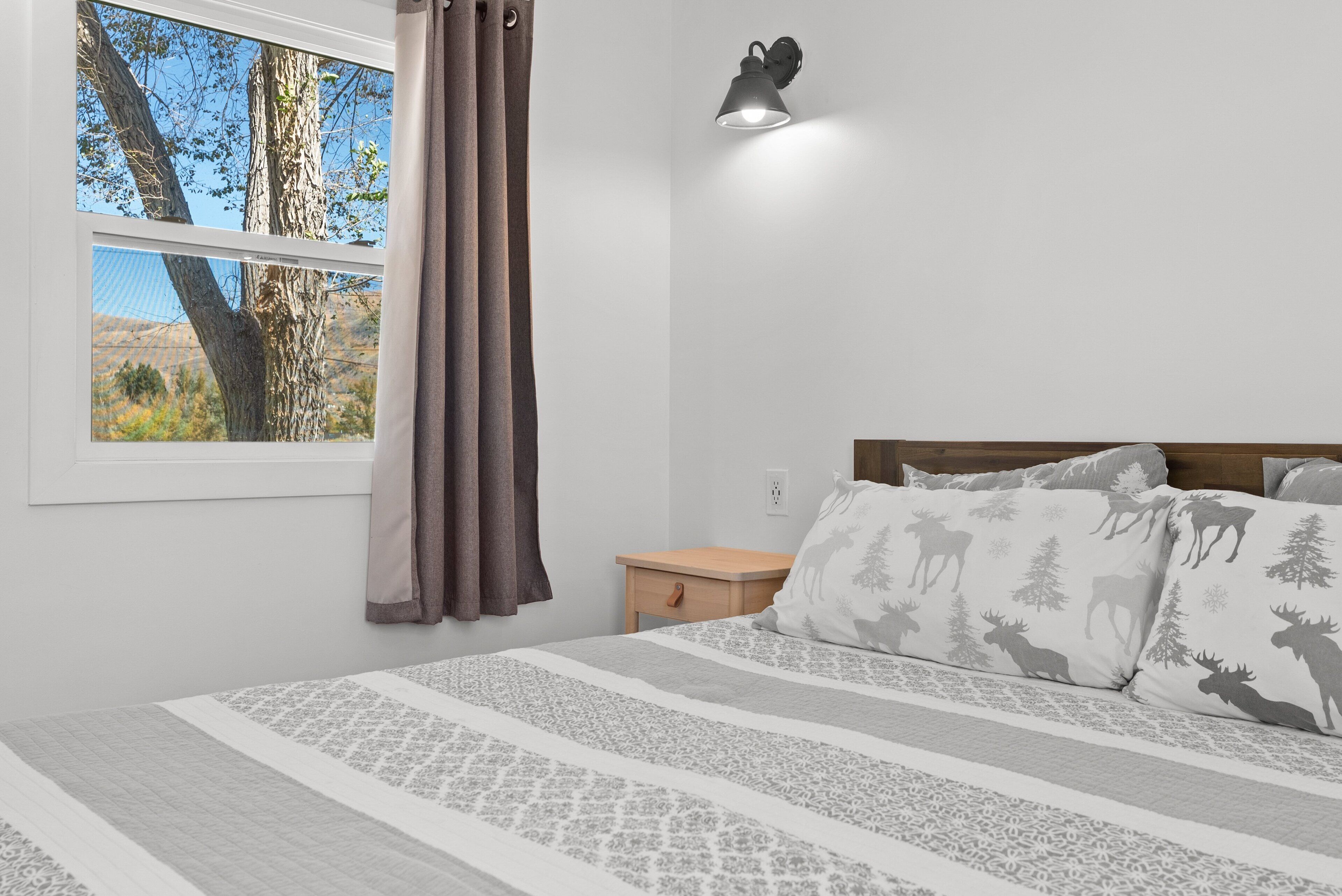 Una camera da letto con un letto, un comodino, una lampada e una finestra con tende.