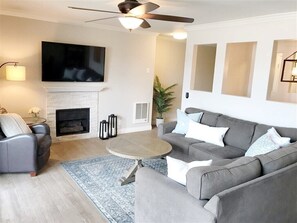 Relax in this stylish living room with a flat-screen TV, fireplace, and comfortable sofa.