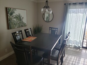 Enjoy meals in this dining area with a table and six chairs, a wall-mounted mirror, and a potted plant.