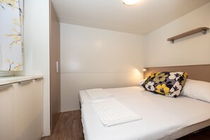 Quarto de hotel com cama, mesa de cabeceira, espelho e janela com cortina.