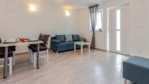 Un salon moderne comprenant un coin repas, un canapé, une table basse et une petite table mise pour un repas.