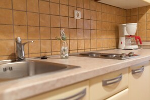 Modern kitchen with a stainless steel sink, coffee maker, and tiled backsplash.