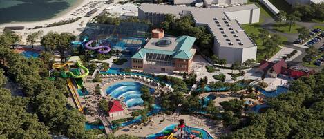 An aerial view of a resort with multiple swimming pools, water slides, and a large building with a green roof.