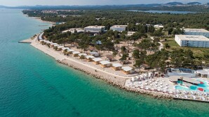 Eine Luftaufnahme eines Küstenresorts mit Unterkünften direkt am Strand, einem Schwimmbad und einer Marina.